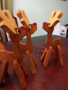 three wooden reindeer figurines sitting on top of a table