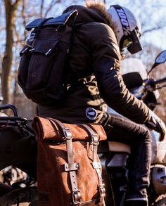 a man riding on the back of a motorcycle with a bag strapped to it's seat