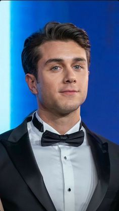 a close up of a person wearing a tuxedo and looking at the camera