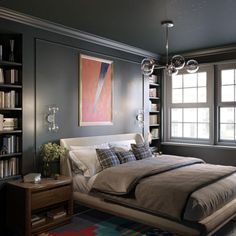 a bedroom with a large bed and bookshelves in front of two windows that look out onto the street