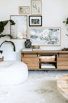 a living room filled with lots of plants and pictures on the wall above it's entertainment center