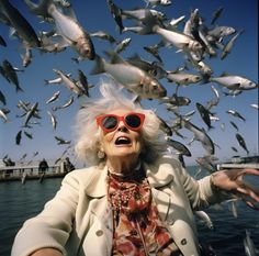 an older woman wearing sunglasses is surrounded by fish