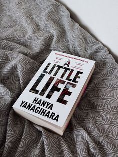 a book sitting on top of a bed next to a gray and white comforter