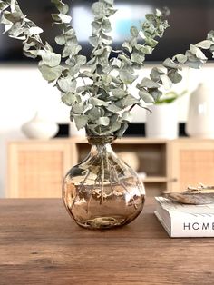 a vase filled with flowers sitting on top of a wooden table next to a book