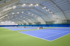 an indoor tennis court with blue and green floors, lights on the ceiling and white walls