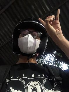 a man wearing a face mask and holding his hand up