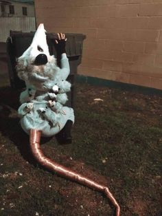 a stuffed animal sitting on top of a grass covered ground next to a metal pipe