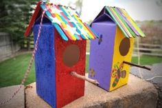 two brightly colored birdhouses on top of a stone wall