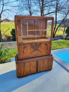 a wooden display case sitting on top of a cement floor next to a swimming pool