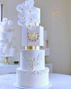 three tiered wedding cake with white flowers and monogrammed initials on the side