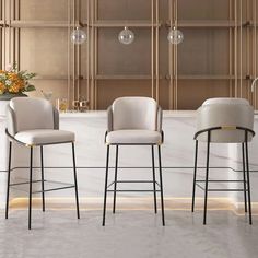 three modern bar stools in front of a marble countertop with flowers on it