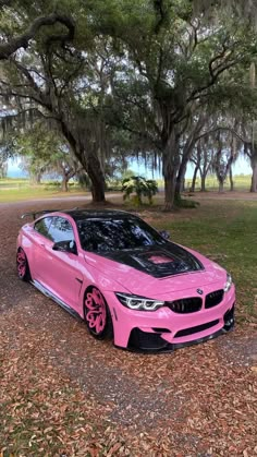 a pink car parked in front of some trees