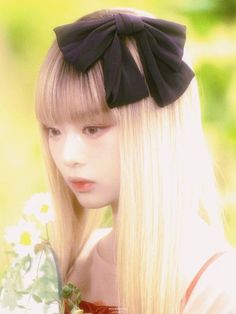 a girl with long blonde hair wearing a black bow headband and holding a bouquet of flowers