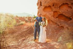 a bride and groom standing in the desert