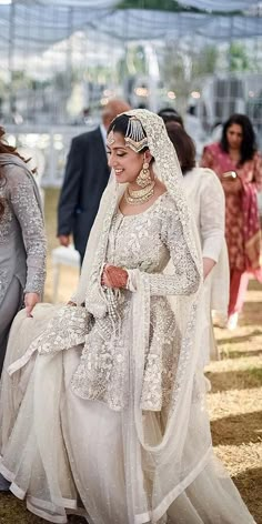 two women dressed in white are walking down the aisle with their wedding guests behind them