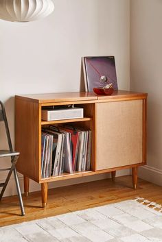 an entertainment center with vinyl records on it and a chair in the corner next to it