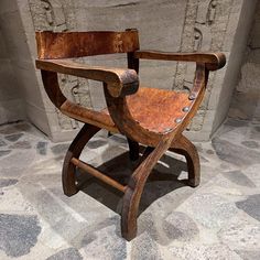 a wooden chair sitting on top of a stone floor next to a brick wall in a room