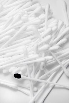 a bunch of white sticks sitting next to each other on top of a table in front of a black dot