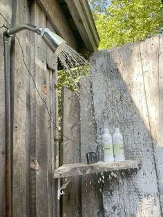 a shower head is sprinkled with water from a hose in front of a wooden shed