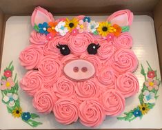 a cake shaped like a pig with flowers on it's head in a box