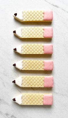 four ice cream sticks with pink and white icing on them, lined up in a row