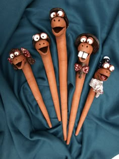 five wooden sticks with faces on them sitting in the middle of a blue cloth covered surface