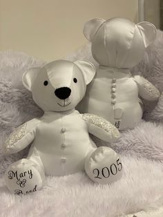 two white teddy bears sitting on top of a fluffy blanket