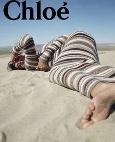 a person laying on the sand with their feet up in the air while wearing striped clothing