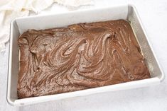 a pan filled with chocolate frosting on top of a counter