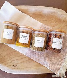 three jars filled with spices sitting on top of a wooden tray next to a white towel