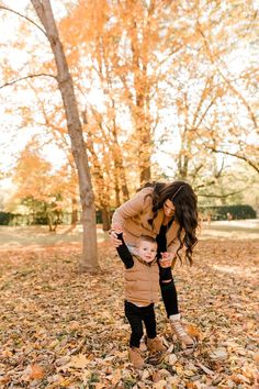 a mother holding her baby in the fall leaves