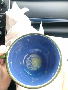 a person holding a blue and green bowl in their hand with tissue paper around it