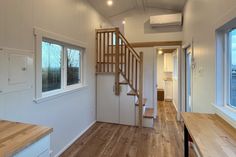 the interior of a tiny house with wood floors and stairs leading up to the loft