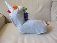 a stuffed animal sitting on top of a white couch next to a pillow with colorful sticks sticking out of it's back