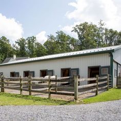 a white barn with green trim and windows