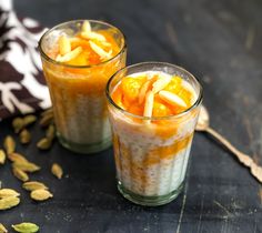 two glasses filled with food sitting on top of a black table next to an orange and white napkin