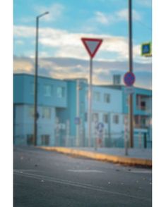 an empty parking lot with two street signs and buildings in the background