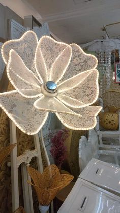 a white flower shaped light hanging from the ceiling in a room filled with furniture and decor