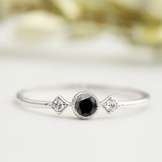 a close up view of a ring with a red stone and two diamonds on it