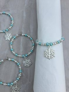 three bracelets with snowflakes on them are sitting next to a napkin holder