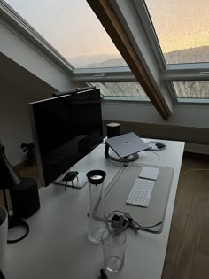 a desk with a monitor, keyboard and mouse on it in front of a window