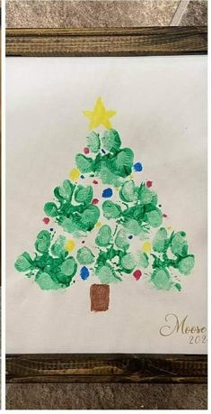 the christmas tree is made with handprints on paper and then placed in a wooden frame