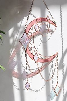 a metal wind chime hanging from a chain next to a potted green plant