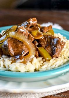 a blue plate topped with rice covered in beef and onions