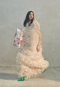 a woman in a white dress holding a shopping bag and wearing green shoes with feathers on it