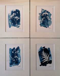 four blue and white paintings hanging on the wall next to each other, one with a fern in it