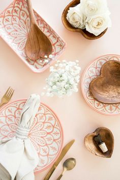 pink and white place setting with wooden utensils, napkins, and flowers