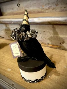 a black and white bird sitting on top of a hat box next to a tag