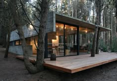 a small cabin nestled in the woods surrounded by trees and lights on it's roof