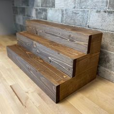 two wooden steps sitting on top of a hard wood floor next to a brick wall